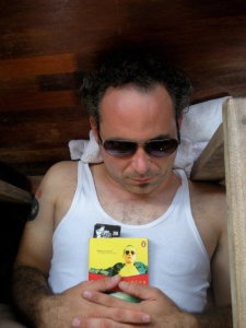 D.D. Miller snoozing on the floor of a boat that is cruising down the Mekong River in Laos. This is the pocketbook edition of Baroque-a-nova. 
